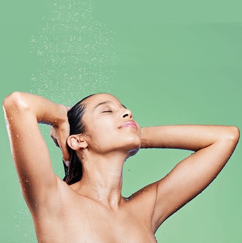 Woman, shower and wash hair in studio, water and blue background for body care or wellness. Morning, bathroom routine and beauty or rinsing treatment, relaxing and hygiene grooming or cleaning