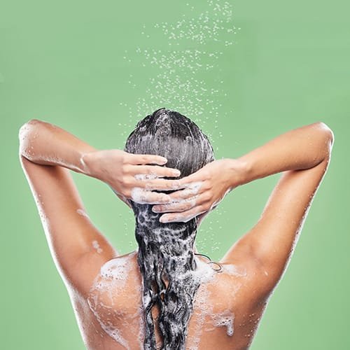 Rinsing it out. Shot of an unrecognizable woman washing her hair in the shower against a blue background.